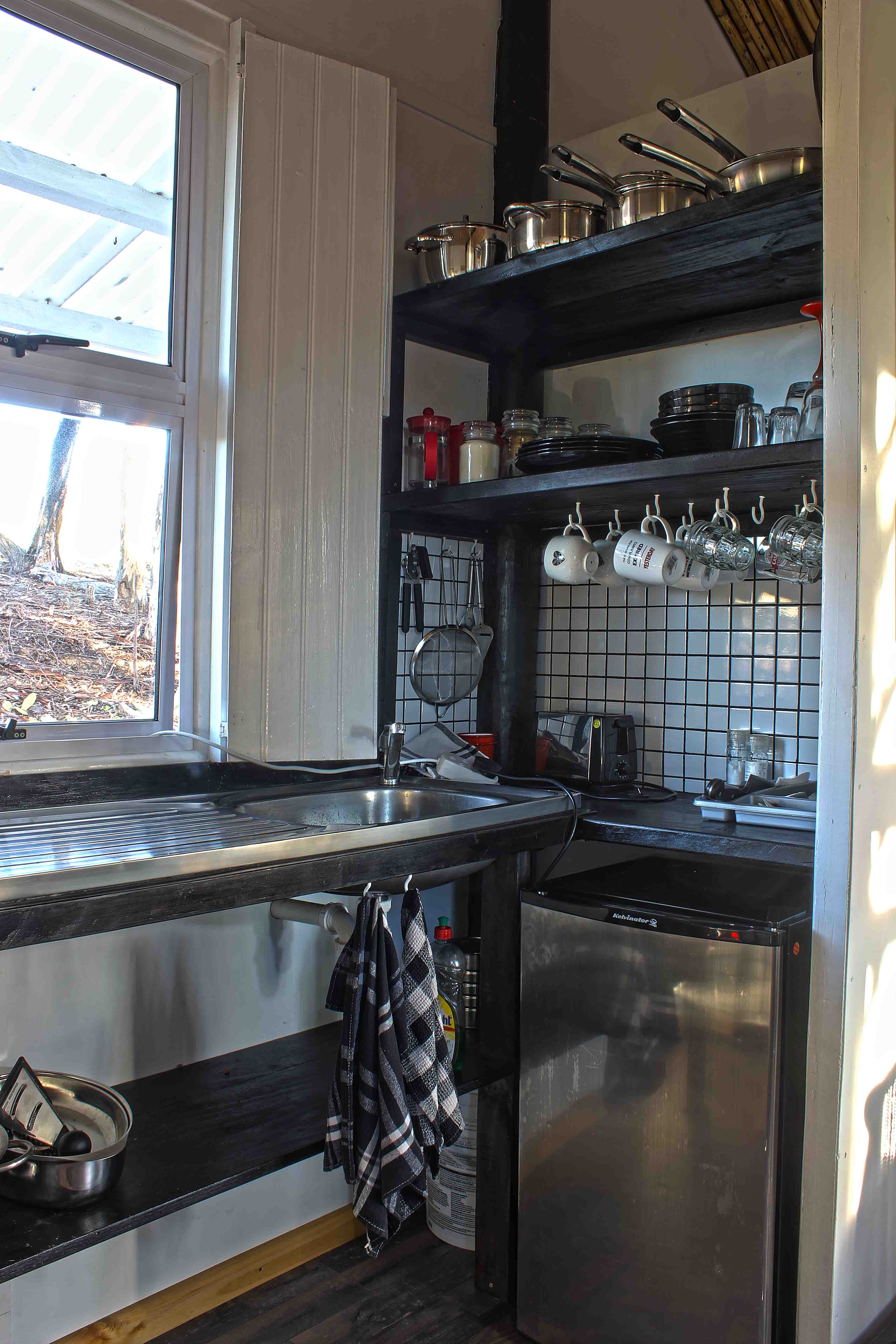 The kitchen of the guest house, with a refrigerator, cutlery and cookware.